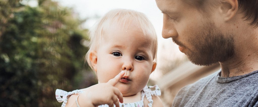 Father holding baby who is touching their lips