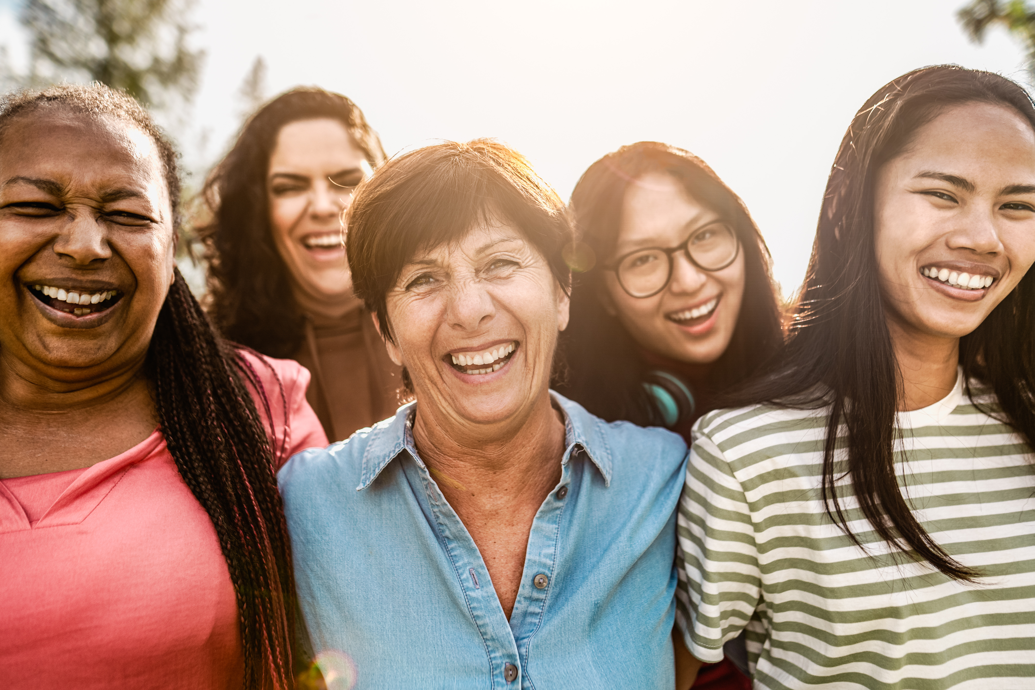 Happy multigenerational women with different ethnicity having fun smiling in front of camera in a public park - Females empowerment concept; Happy multigenerational women with different age and ethnicity having fun smiling in front of camera in a public park